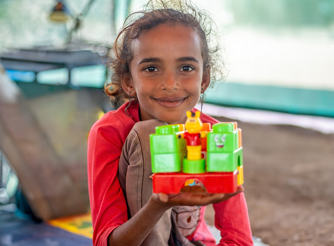 Une fille souriante tient un jouet éducatif.