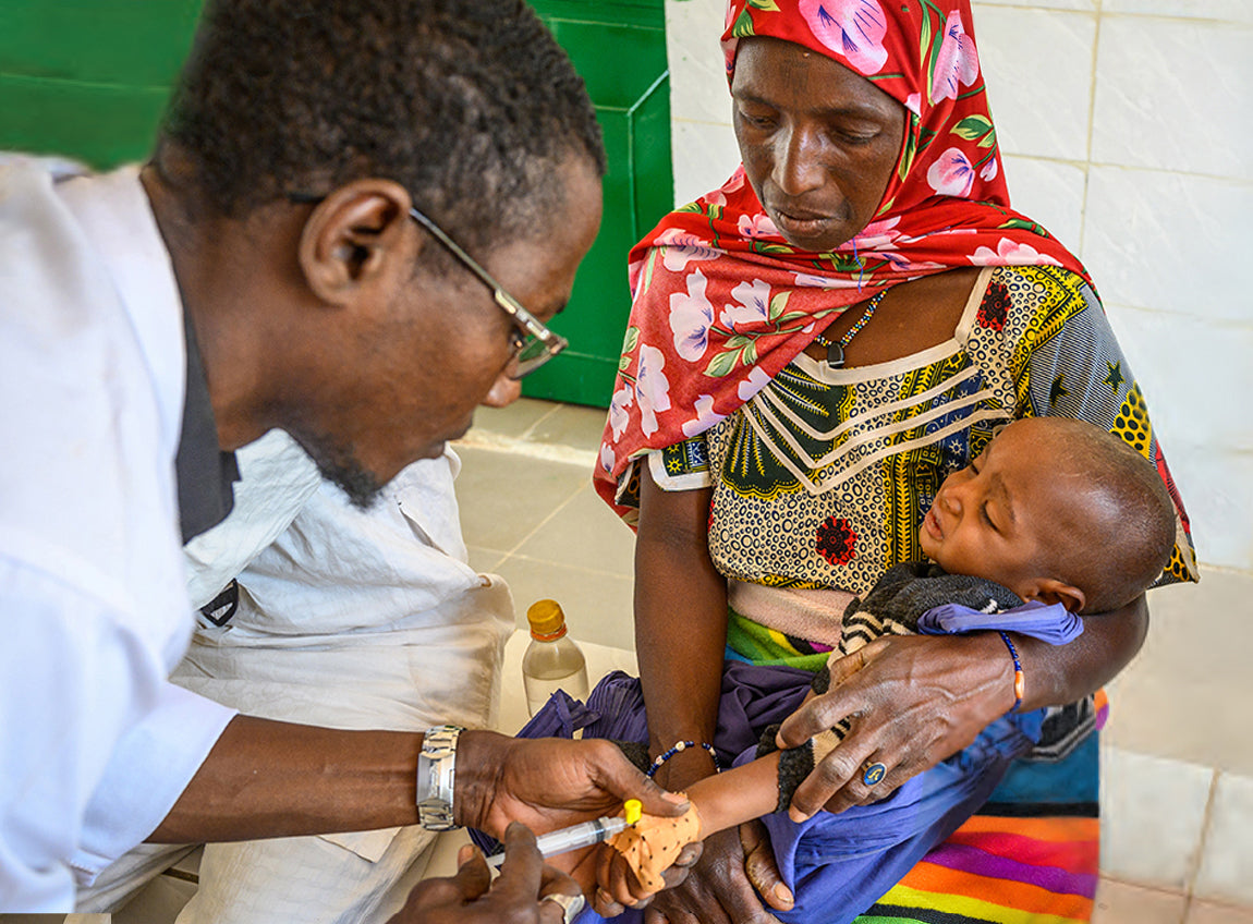 Une femme tient son bébé dans ses bras alors qu’il se fait vacciner par un médecin.
