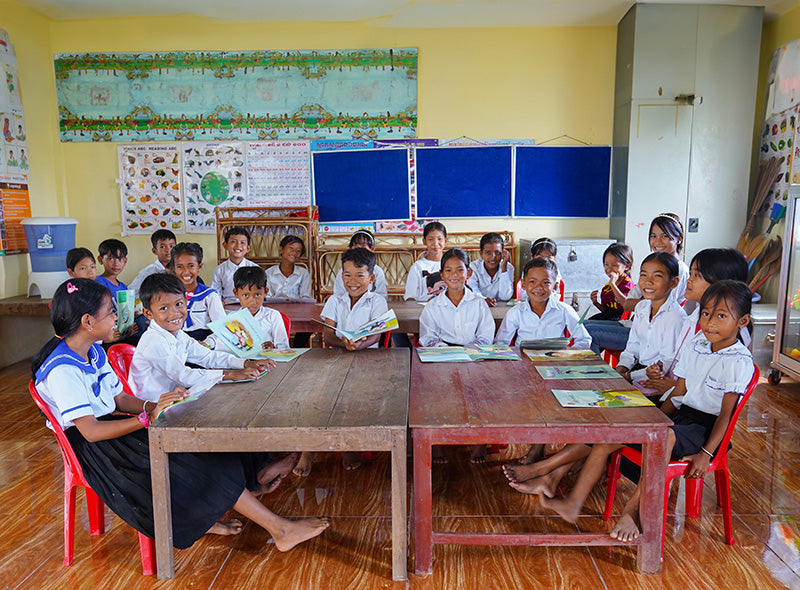 Les enfants sourient assis à leur bureau dans une salle de classe.