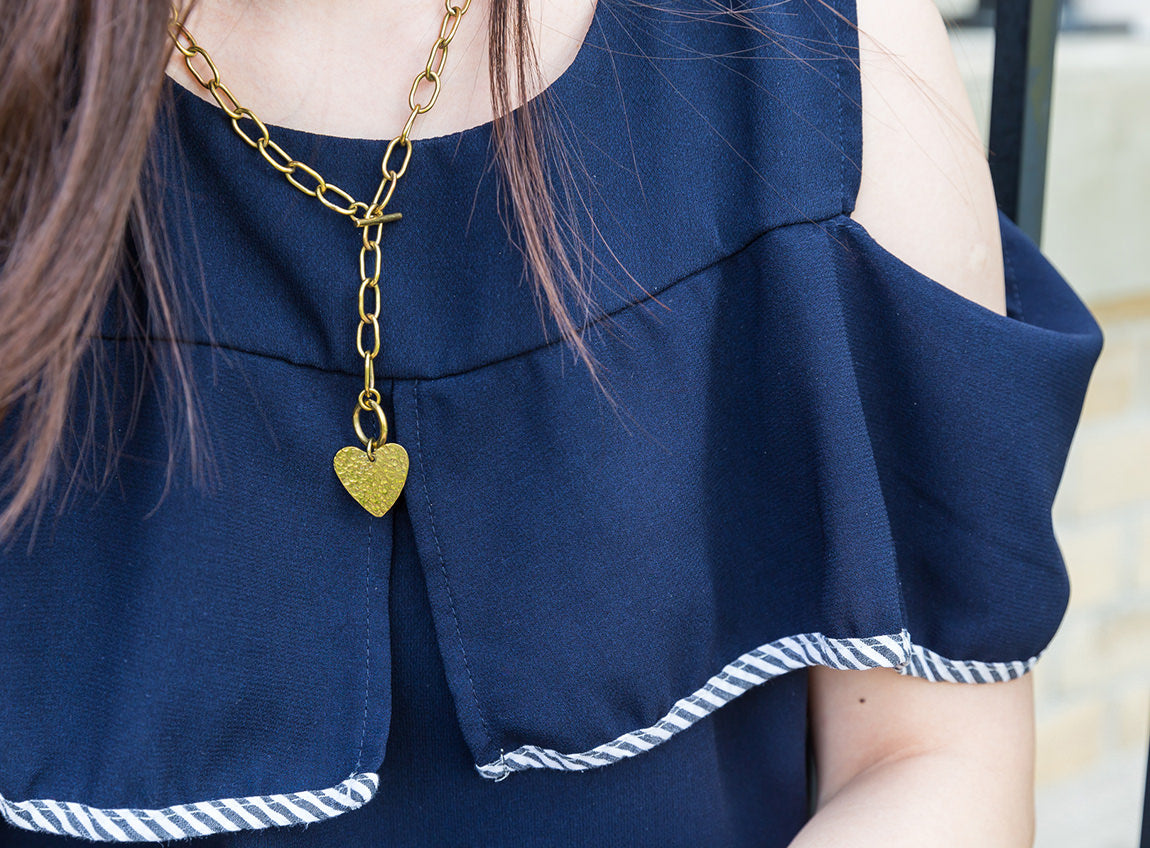 Le haut du corps d’une fille aux cheveux longs portant le collier en chaîne avec pendentif en forme de cœur.