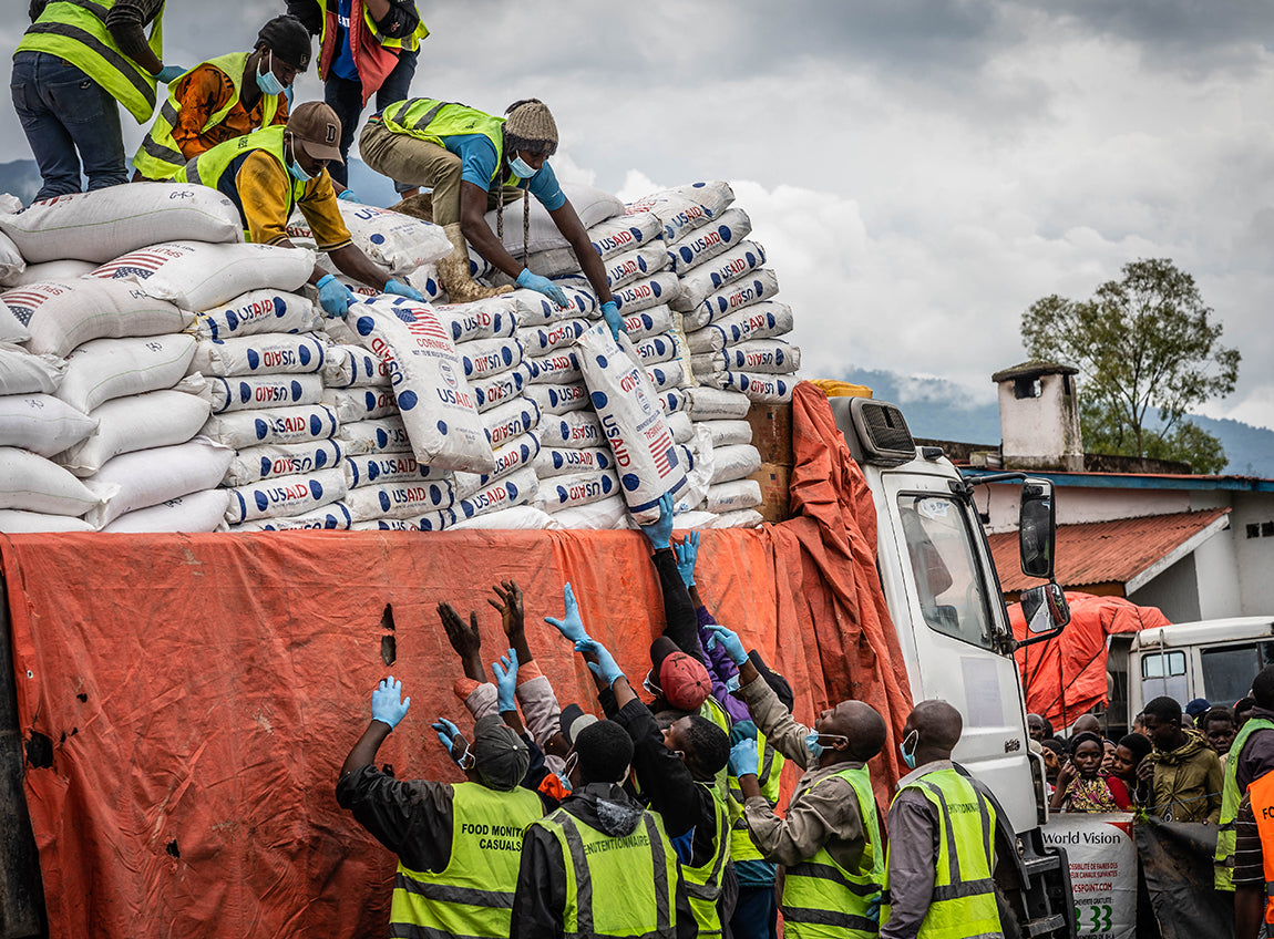 Des bénévoles reçoivent de grands sacs d’aide alimentaire d’urgence distribués par d’autres bénévoles se tenant sur le toit d’un camion.