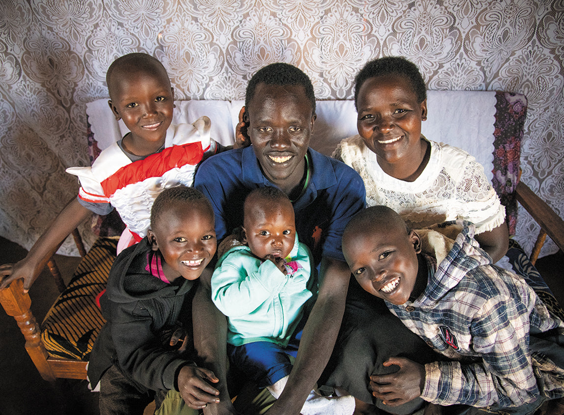 Un homme et cinq enfants s’étreignent chaleureusement tout en souriant au photographe.