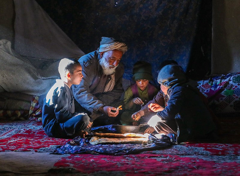 Un père et ses enfants se rassemblent en cercle pour manger.