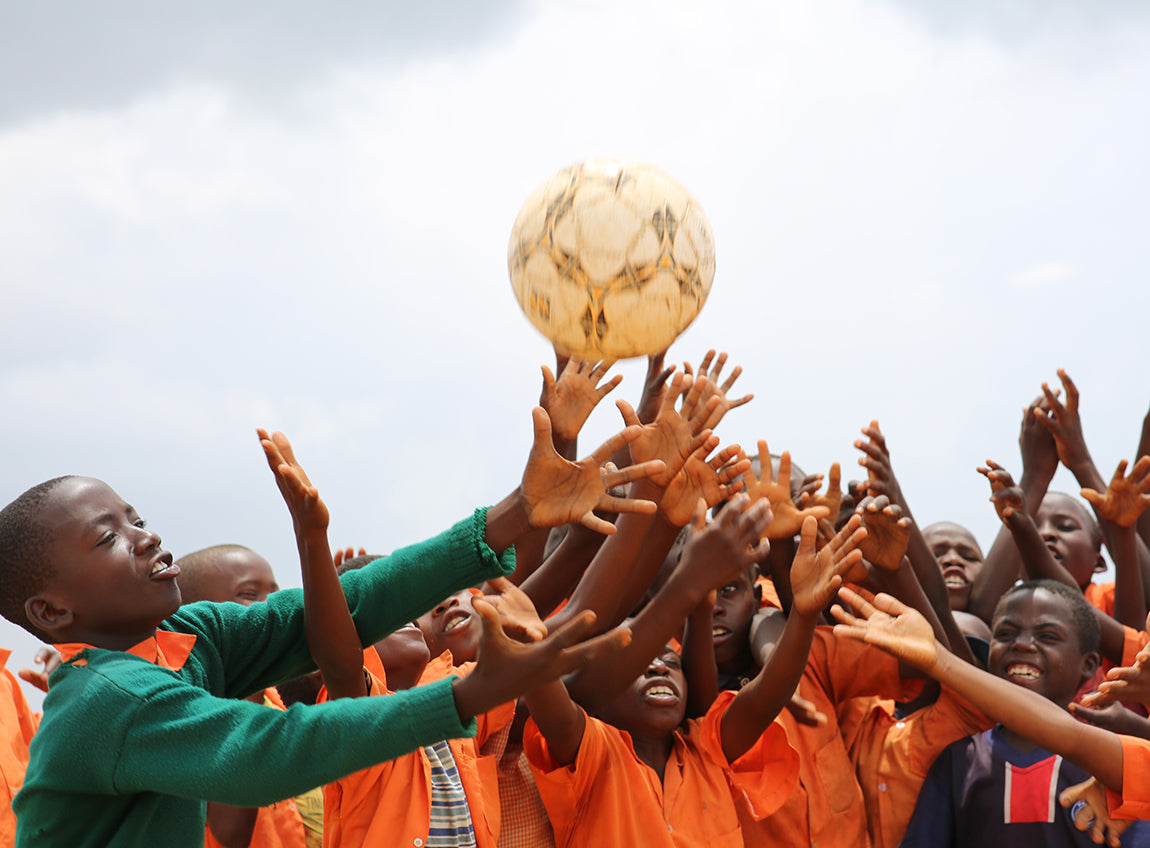 De nombreux enfants tendent les bras vers un ballon de soccer en l’air.