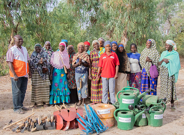 Les membres d’une communauté sourient derrière les outils fournis par Vision Mondiale.