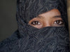 Gros plan sur une jeune fille : son foulard noir ne laisse apparaître que ses yeux.