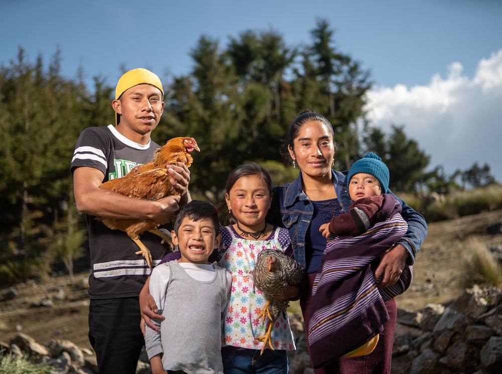 Une famille de cinq personnes sourit à l’objectif. Ils tiennent deux poulets dans leurs bras.