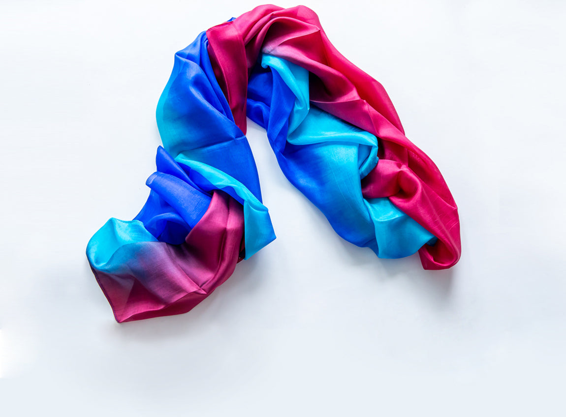 Une écharpe en soie aux couleurs bleues, rose et violettes éclatantes.
